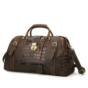 The Crocodile Pattern Leather Travel Bag is a large brown genuine leather duffel bag that features a crocodile skin pattern, gold-tone hardware, and multiple buckle straps. It has dual top handles, a shoulder strap, a front clasp closure, and a spacious interior.