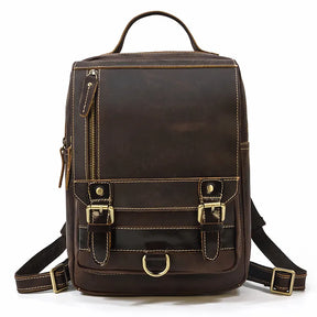 The Leather Travel Daypack Shoulder Bag is a versatile daypack crafted from genuine cowhide leather in brown, highlighted with beige stitching and silver hardware. It features two front buckle straps, a vertical zipper pocket on the left side, and a top handle. This travel bag also includes adjustable straps and a D-ring detail at the bottom front.