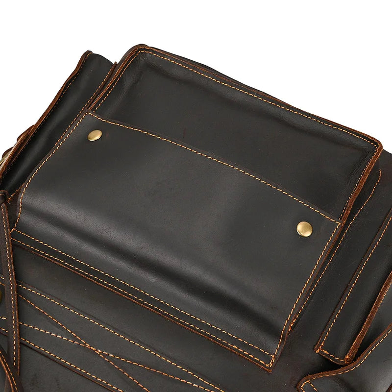 Close-up of a Genuine Leather Travel Backpack made from black cow leather with brown stitching. The backpack features a large front pocket secured by two brass snap buttons. The detailed stitching and texture of the durable material are visible, with other sections of the backpack partially shown.