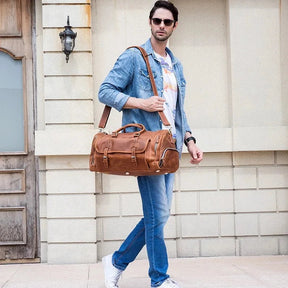 Man carrying Weekender 20 Leather Travel Bag; stylish mens leather duffle bag with shoe compartment and multiple pockets.