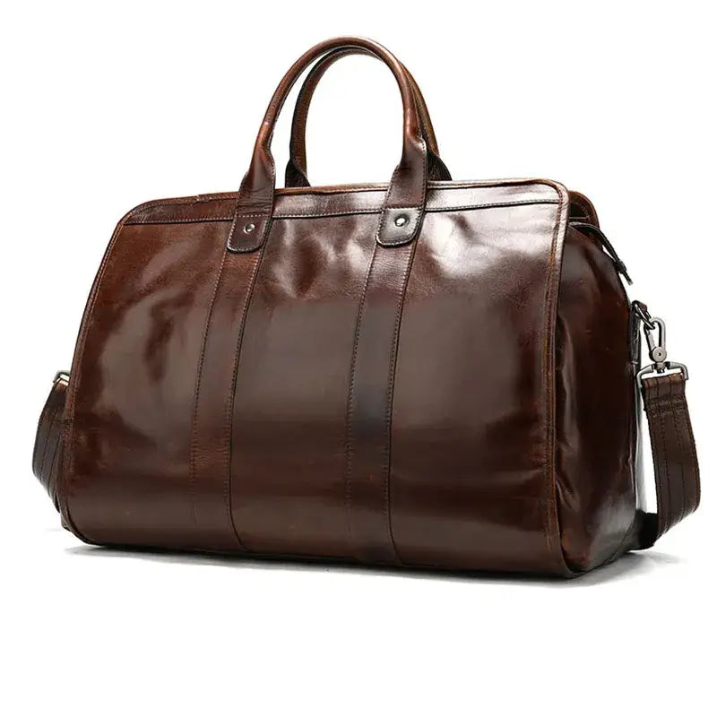 The Unisex Genuine Leather Travel Duffle Bag is a large, polished brown bag featuring dual handles, a detachable shoulder strap, and detailed horizontal stitching. This handcrafted duffle bag boasts a structured design and ample space, making it an ideal choice for travel or commuting.