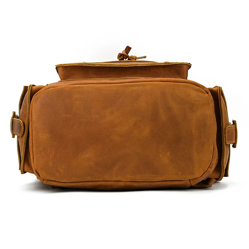 A tan Genuine Leather Travel Backpack made from durable cow leather is shown from the front. The backpack has a smooth texture, two side pockets with buckle closures, and a top handle. The main compartment zipper appears partially open. Its vintage aesthetics and simple, classic design make it perfect for any journey.