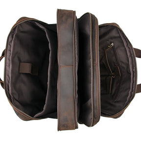 The Leather 17" Business Travel Briefcase, made of genuine brown leather, is open to reveal its interior. It features three main compartments with various pockets, including a zippered pocket and a padded laptop compartment. The durable material and adjustable strap offer comfort and organized storage options.