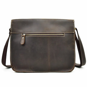 The Leather Business Travel Shoulder Bag is a brown crossbody messenger bag crafted from genuine cowhide leather. It features a long, adjustable strap and showcases white stitching along the edges. There's a horizontal zipper pocket on the front with a leather pull tab, and high-quality alloy hardware adds to its slightly worn, vintage appearance.