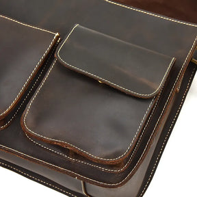 Close-up view of the Leather Business Travel Shoulder Bag, crafted from dark brown genuine cowhide leather with a smooth texture and accented by white stitching. It features two front pockets with flap closures, and the prominently visible stitching enhances its design.