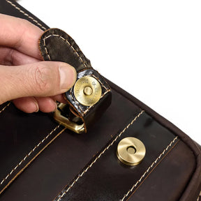 Close-up of a hand opening the magnetic button closure of the Leather Travel Daypack Shoulder Bag in dark brown, genuine cowhide leather with visible stitching. The focus is on the clasp and the person's fingers, highlighting this versatile daypack's brass hardware around the closure area.