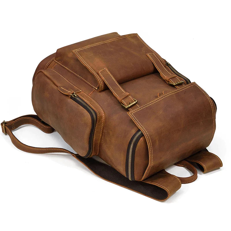 The Vintage Leather Travel Backpack is a stylish brown, genuine cowhide leather bag with two shoulder straps, multiple zippered compartments, brass buckles, a spacious design, sturdy construction, and a dedicated laptop compartment.