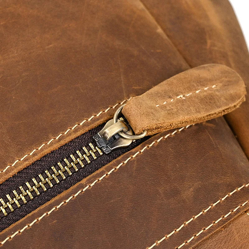 Close-up of the Genuine Leather Vintage Backpack, highlighting a detailed view of the stitching and a metal zipper with a leather pull tab. The smooth texture of the genuine leather emphasizes quality craftsmanship.