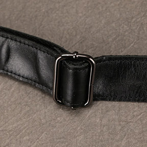 Close-up of the Leather Belt Bag's black cowhide leather strap, featuring a metallic rectangular buckle made from durable alloy hardware. The image highlights the intricate details of the buckle and the texture of the genuine leather strap, set against a textured beige background.