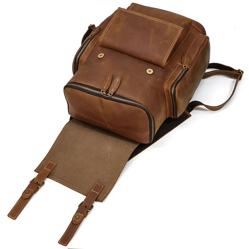 The Vintage Leather Travel Backpack, crafted from genuine cowhide leather, features an open flap displaying ample storage, multiple compartments including a laptop pocket, and buckled straps—highlighting its rugged and stylish design.