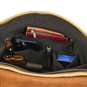 The Canvas & Leather Vintage Messenger Bag, featuring a business style similar to briefcases, showcases its contents: a brown leather-bound wallet, a smartphone pocket, a pen, tissues, and neatly arranged small items. Made from genuine leather with organized sections and a zippered pocket.