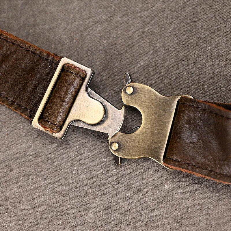 Close-up of the Leather Belt Bag made from genuine cowhide leather, showcasing durable alloy hardware with a quick-release buckle laying on a textured grey surface. The unique design of the buckle features a lever mechanism for easy fastening and unfastening, while the worn and aged appearance of the leather adds character to the bag.