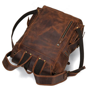 The Genuine Leather Travel Backpack in Light Brown features adjustable shoulder straps, multiple pockets, zipper closures, and brass hardware. With its rugged, worn look, black mesh padding on the back for comfort, and a top handle for versatile carrying options, this backpack is an ideal addition to your durable travel gear.