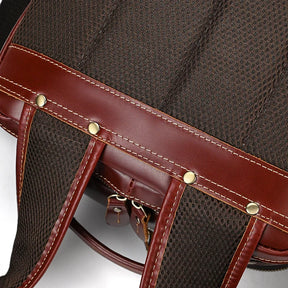 Close-up of the Vintage Leather Travel Backpack in stylish brown and dark maroon, featuring sturdy shoulder straps with brass rivets and reinforced stitching. Made from genuine cowhide leather, this textured pattern offers both durability and aesthetic appeal.