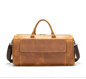 The Vintage Genuine Leather Travel Duffle Bag is crafted from authentic cow leather in a brown hue. It boasts two handles and a detachable shoulder strap, along with a front pocket and classic design on a plain white background, ensuring a premium travel experience with its spacious interior.