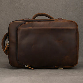 A Vintage Leather Travel Backpack in brown, featuring a handle and two zippers, set against a plain background. The leather showcases a smooth, polished finish, giving the backpack a timeless appeal and medium size.