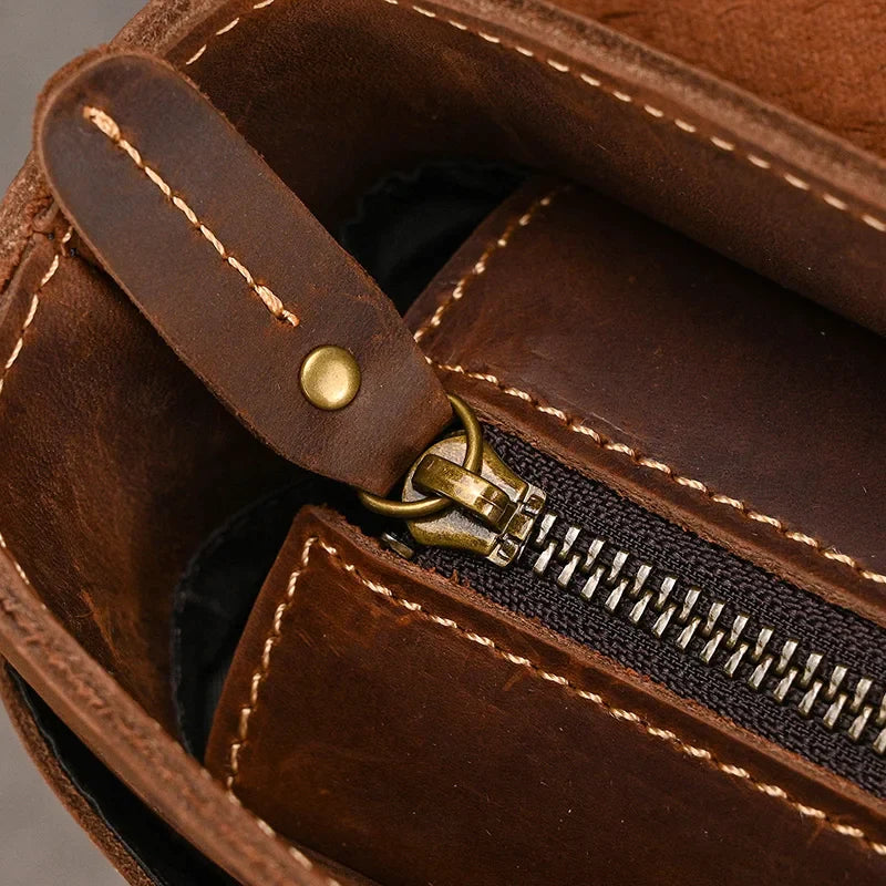 Close-up of the interior of a Leather 14" Briefcase Shoulder Bag featuring a zipper with a brass pull tab. The zipper is partially open, revealing the inner pocket and stitching details. The genuine cowhide leather has a rich, textured appearance with visible seam stitching, exuding professional style.