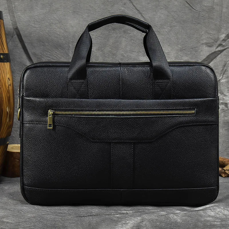 The 16" Leather Briefcase is showcased against a grey backdrop, featuring a stylish design with two sturdy handles, a front zipper pocket, and an adjustable strap. Its sleek design, textured material, and clean lines highlight its professional and elegant appearance.