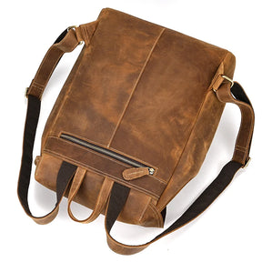 The Genuine Leather Vintage Backpack for men showcases a distressed, vintage appearance with a convenient front zipper pocket and adjustable straps. Designed to complement a casual style, it is pictured lying flat against a white background.