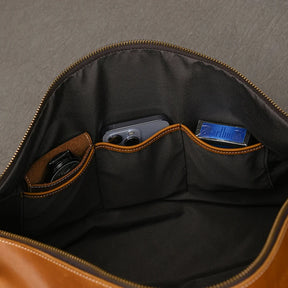 The image shows the inside of a Leather Travel Duffle, a vintage brown bag with three sections holding a watch, smartphone, and pack of gum. The bag is open, revealing the soft, dark lining of its genuine leather.