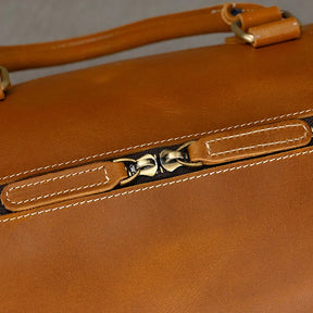 Close-up of the Leather Travel Duffle, highlighting its brown genuine leather with a smooth vintage feel, featuring a metallic zipper and contrasting white stitching. The centered image captures the zipper pull.