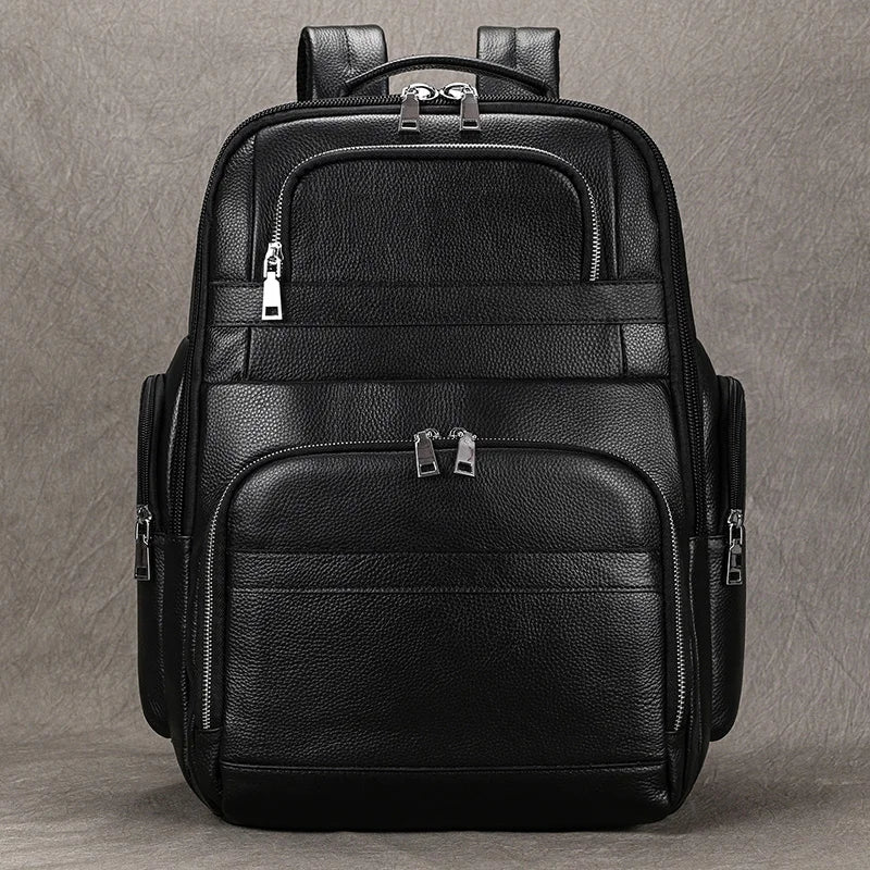 The Black Leather Travel Backpack is showcased against a plain gray background, featuring multiple zippered compartments. Its sleek, minimalist design includes silver zipper accents, a spacious interior, and padded shoulder straps for enhanced comfort.