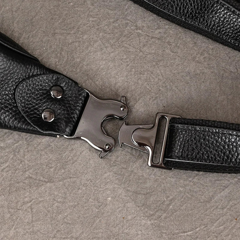 Close-up image of a black leather strap with a metal quick-release buckle, laid out on a textured gray fabric surface. The Black Leather Belt Bag strap features two silver rivets near the buckle, and the premium leather has a pebbled texture, showcasing its versatile design.