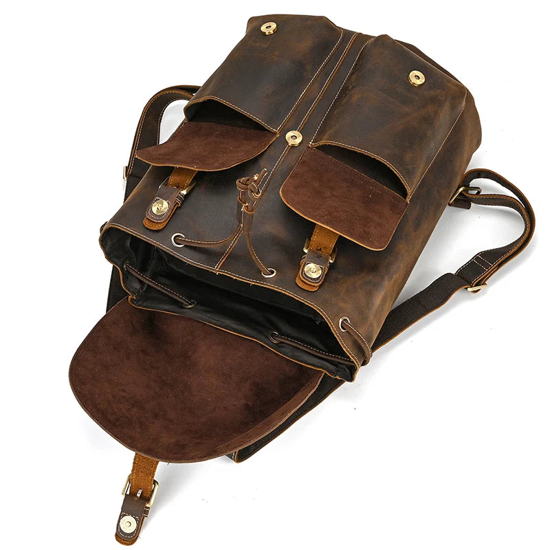 Introducing the Genuine Leather Vintage Backpack: This vintage-style brown leather softback backpack features two front pockets and a buckle closure. Ideal for casual outings, it boasts an open top that reveals a spacious interior. The genuine leather straps and metal accents further accentuate its classic design.