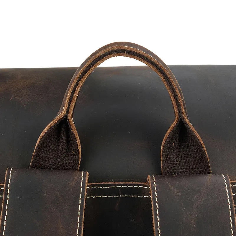 Close-up of the Vintage Leather Travel Backpack's rustic brown cowhide leather handle, featuring visible stitching and strap attachments. The distressed finish adds to its vintage aesthetic, perfect for a classic look.