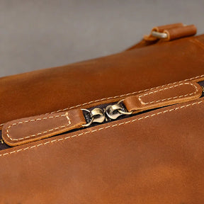 Close-up of the Weekender Duffle 22 Leather Travel Bag showcasing its genuine cowhide leather, intricate stitching, and two centrally positioned metal zippers. The texture of the high-quality leather is clearly visible, emphasizing its superior material. The blurred background enhances the focus on the travel bag's craftsmanship.