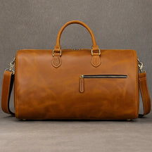 The large vintage Leather Travel Duffle, made from genuine brown leather, has a top handle, adjustable shoulder strap, front zippered pocket, and metallic hardware. It's perfect for travel bag enthusiasts seeking style and functionality.