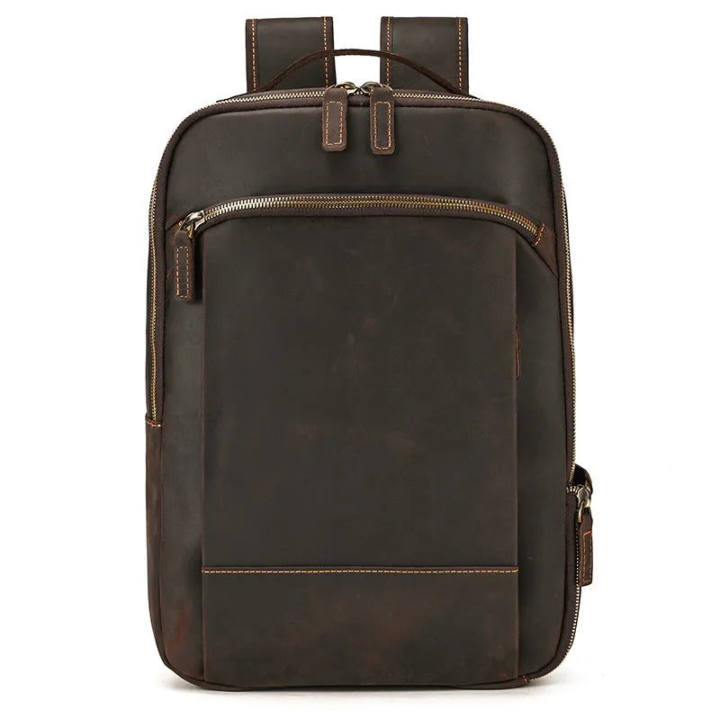 The Vintage Leather Daypack is displayed, showcasing its rectangular design in brown genuine cowhide leather. It includes a small front zipper pocket, a spacious main compartment, two adjustable shoulder straps, and a top handle. The slightly distressed finish adds to its rustic and vintage charm.