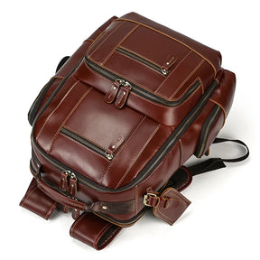 The Vintage Leather Travel Backpack is crafted from genuine cowhide leather and features multiple zippered compartments, including a spacious main compartment and several smaller pockets for ample storage. It has adjustable black shoulder straps, metal hardware, and stitching accents for durability and style.