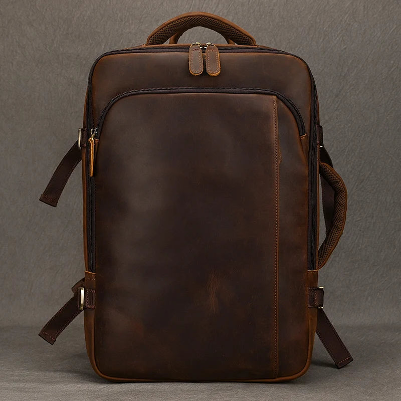 Introducing the Vintage Leather Travel Backpack - a chic men's accessory made from authentic leather, showcasing a modern, minimalist aesthetic. It comes equipped with a spacious front pocket, adjustable shoulder straps, a sturdy top handle, and elegant zippers, all beautifully complemented by a plain gray backdrop.