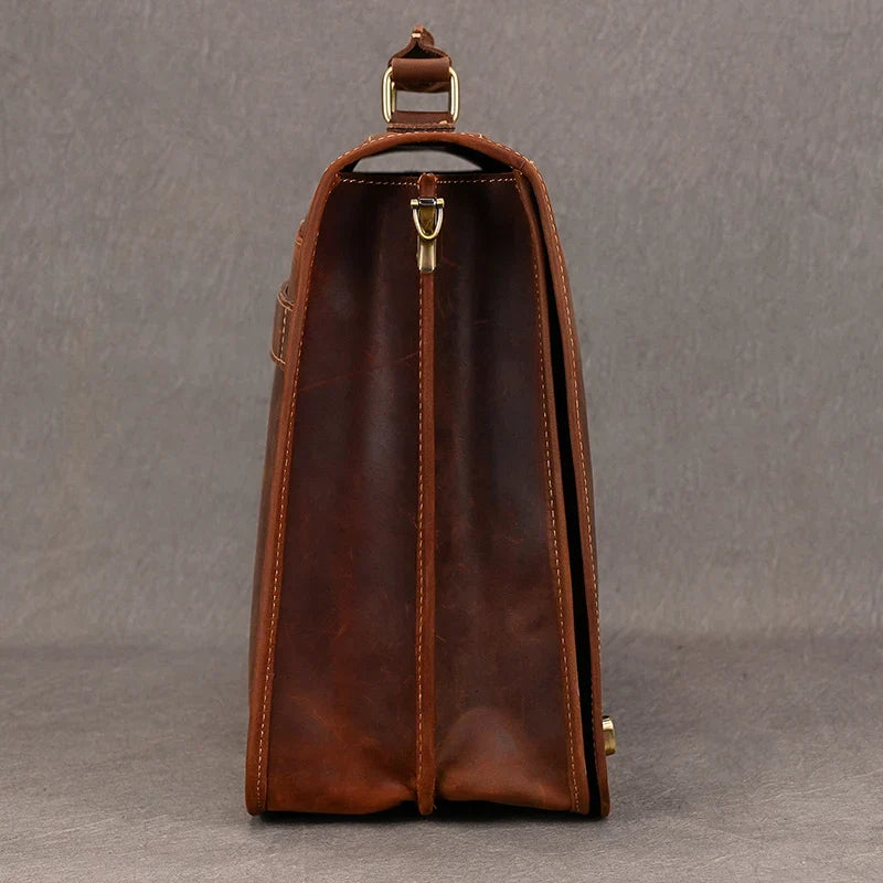 Side view of the Vintage Leather Briefcase made from genuine leather, featuring visible stitching and brass hardware. The briefcase is pictured against a plain gray background, showcasing its structured design, handle, and metal hooks. Ideal for maintaining a professional image, it even includes a laptop compartment for added convenience.