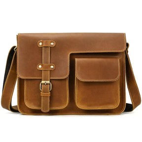 The Leather Business Travel Shoulder Bag is crafted from genuine brown cowhide leather and features a front flap secured by a strap and buckle. It includes two front pockets with flap closures, visible stitching around the edges, and alloy hardware, along with an adjustable shoulder strap perfect for business travel.