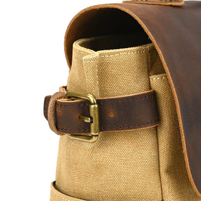 Close-up of the Canvas & Leather Vintage Messenger Bag. It features a beige canvas body with a genuine leather flap and a side strap with a brass buckle. The textures showcase its craftsmanship, offering a business-style men's briefcase look.