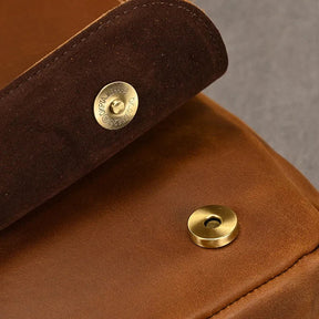 Close-up of the Vintage Leather Shoulder Bag showcasing its fastening mechanism. The bag's flap is open, revealing a brass snap button. Crafted from genuine cow leather, the interior of the flap features a soft, suede-like finish that exemplifies timeless style.