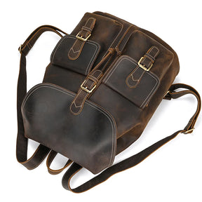 Introducing the Genuine Leather Vintage Backpack: a classic brown softback crafted from high-quality leather. It features two buckle-closure front pockets and a spacious bottom pocket. The backpack is designed with adjustable shoulder straps and detailed stitching, offering a rugged yet casual and stylish appearance.