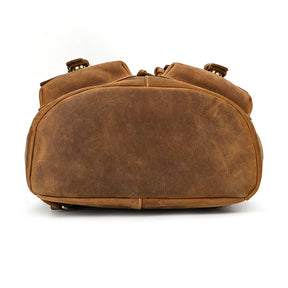 The image depicts the bottom view of a Genuine Leather Vintage Backpack designed for men. It features brown genuine leather with visible stitching, showcasing a rugged, durable texture perfect for a casual style. The backpack looks slightly worn, suggesting it has been used.