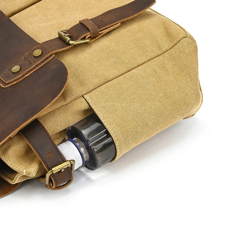 A Canvas & Leather Vintage Messenger Bag features tan canvas and brown cow leather straps and buckles. A chic black and white water bottle peeks from the side pocket, adding sophistication to this men's business briefcase.