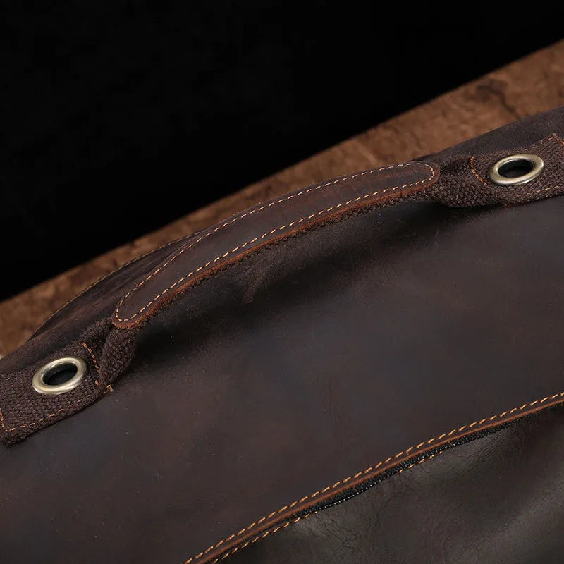 Close-up of a genuine cowhide leather handle on the Vintage Leather Travel Backpack, featuring visible stitching and metal eyelets against a dark surface. The rich brown leather showcases a smooth texture and detailed craftsmanship, ideal for the stylish traveler.