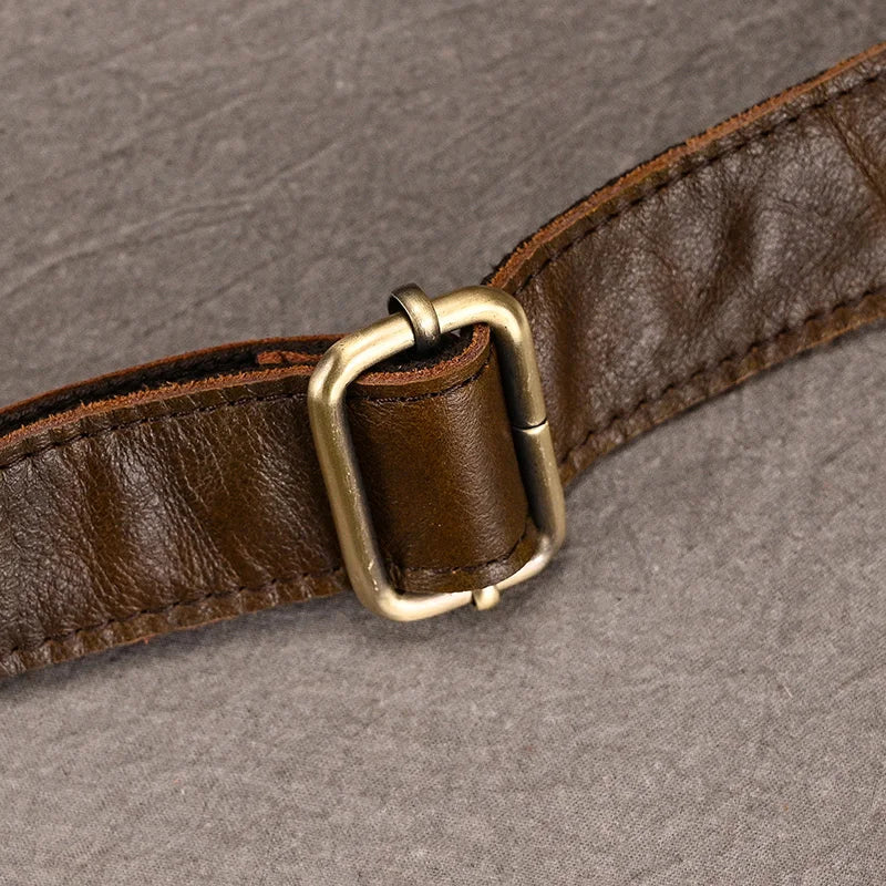 A close-up of the brown Leather Belt Bag with a brass buckle on a grey background. Made from genuine cowhide leather, the belt bag's slightly worn appearance showcases subtle creases and texture. The simple, classic design of the durable alloy hardware buckle complements the neatly stitched leather bag perfectly.