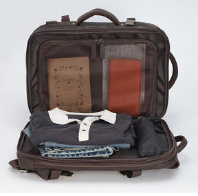 A brown suitcase is open, showcasing neatly packed items: a folded navy polo shirt, jeans, a rolled-up black garment, and various notebooks in mesh pockets. Nearby sits the Vintage Leather Travel Backpack, its genuine leather exterior adding a touch of elegance against the plain white background.