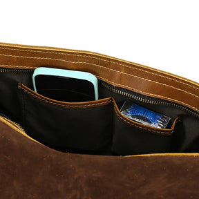 A close-up view of the interior pocket of the Vintage Shoulder Bag. There is a mint green smartphone in one pocket and a packet of tissues in another, both secured within the zippered compartments. The stitching, durable alloy hardware, and lining of the genuine cowhide leather bag are clearly visible.