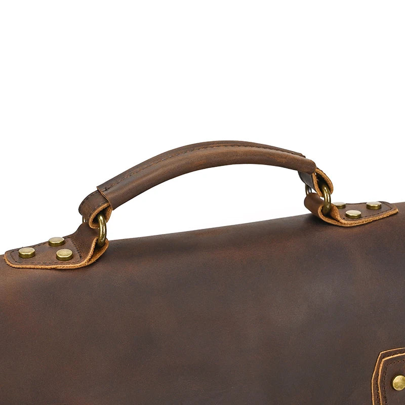 Close-up of the handle from the Canvas & Leather Vintage Messenger Bag, revealing its smooth brown cow leather texture with metal rivets and gold-toned rotating clasps at both ends.