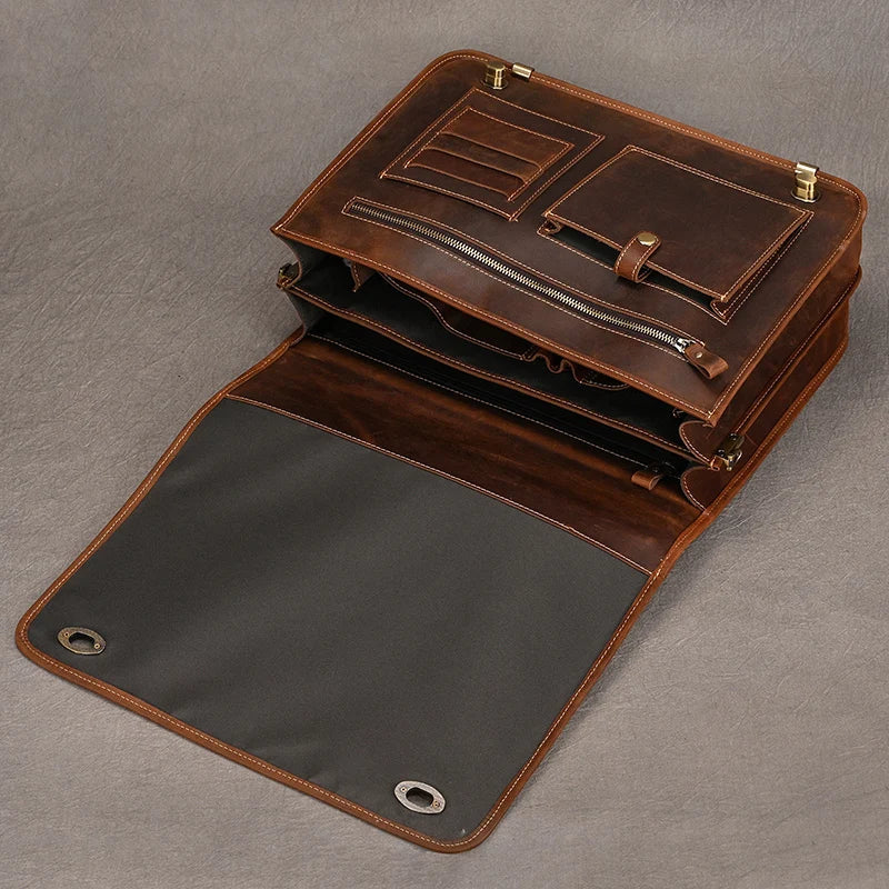 The Vintage Leather Briefcase is open, revealing its brown genuine leather exterior and multitude of compartments and pockets crafted to project a professional image. Inside, the dark-lined flap features metal grommets at each corner. The organized layout includes card slots, a zipper pocket, dedicated spaces for documents, and a laptop compartment.