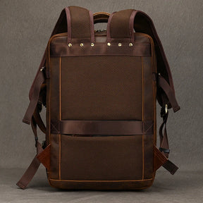 The Vintage Leather Travel Backpack is a handcrafted, genuine leather piece that showcases a rectangular shape in brown. It is designed with mesh padding, adjustable straps, and metal studs at the top to enhance its vintage appearance against a dark textured background.