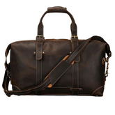 Introducing the Weekender 20 Leather Travel Duffle: a large brown leather duffle bag featuring sturdy handles and a removable shoulder strap. Crafted from genuine cowhide leather, it boasts brass hardware, accent stitching, and multiple straps for a rugged look. The bag offers a spacious main compartment along with side pockets for extra storage.