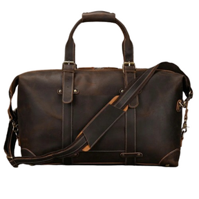 Introducing the Weekender 20 Leather Travel Duffle: a large brown leather duffle bag featuring sturdy handles and a removable shoulder strap. Crafted from genuine cowhide leather, it boasts brass hardware, accent stitching, and multiple straps for a rugged look. The bag offers a spacious main compartment along with side pockets for extra storage.